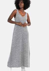 Szara dzianinowa, bezrękawnikowa sukienka maxi z głębokim dekoltem w szpic. Miękka tekstura i sylwetka w kształcie litery A, opadająca do kostek.