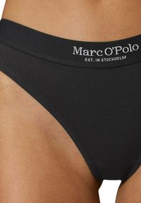 Bikini underwear in cotone nero con una morbida vita elastica, caratterizzata da un ricamo bianco con il marchio: "Marc O'Polo EST. IN STOCKHOLM."