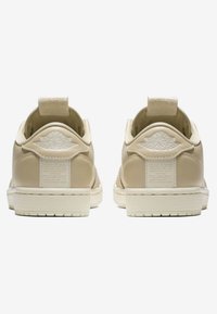 Beige Leder-Sneaker mit einem strukturierten Fersenband. Weiße Gummisohle, geprägtes Logo an der Ferse und Stoffakzente auf der Rückseite.