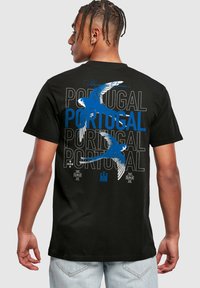 Černé bavlněné tričko s modrými a bílými grafikami ptáků a opakujícím se textem "PORTUGAL". Krátké rukávy a standardní střih.