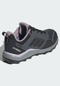 Chaussure de sport noire avec des accents gris, tige en mesh et semelle texturée. Comprend un col rembourré, un système de laçage et des marquages TERREX.