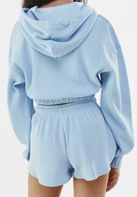 Ljusblå, våffeltexturerad hoodie och matchande shorts med elastisk midja. Låst passform, långa ärmar och hoodie med dragsko.
