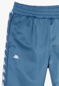 Pantaloni atletici blu realizzati in tessuto leggero. Caratterizzati da una cintura elastica, tasche laterali e dettagli con logo bianco lungo la cucitura.