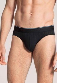 Schwarze Baumwollslips mit gerippter Textur und einem elastischen Bund mit dezentem Logo. Klassischer Schnitt mit minimaler Abdeckung.