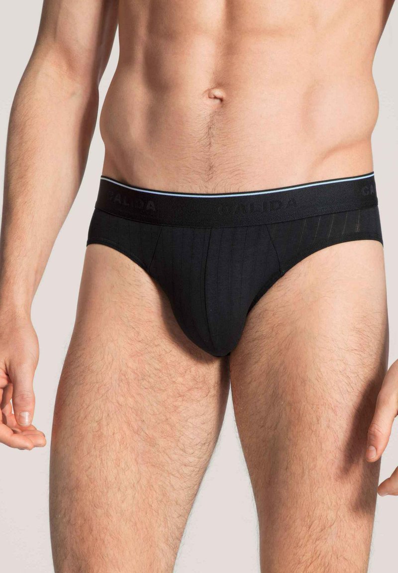 Schwarze Baumwollslips mit gerippter Textur und einem elastischen Bund mit dezentem Logo. Klassischer Schnitt mit minimaler Abdeckung.