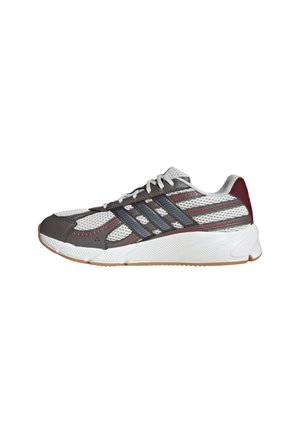 Scarpa sportiva bianca e grigia con strisce nere, dettagli rossi, lacci bianchi e una suola spessa bianca con suola di colore gomma.