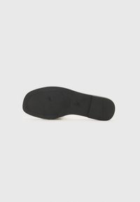 Zwarte schoenzool met een gladde, gestructureerde afwerking. Heeft een afgeronde vorm en een lichte hak. Minimalistisch design zonder zichtbare patronen of accenten.