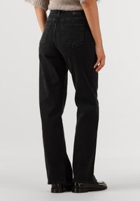 Svarta denimjeans med rak bendesign, med två bakfickor och hög midja, matchade med svarta skor.