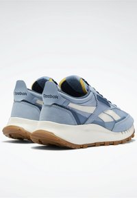 Blå sportskor med en mix av mocka och mesh överdel. Har vita accenter och en texturerad gummisula. Dämpad krage för komfort.