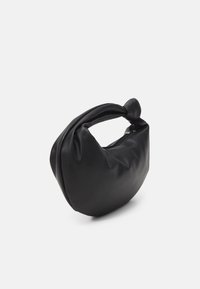 Sac à main en cuir noir souple avec une forme arrondie et un détail de nœud sur la poignée, présenté sur un fond blanc uni.