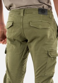 Pantaloni cargo verde oliva realizzati in tessuto resistente, con due tasche posteriori, un'etichetta nera in vita e una vestibilità comoda con tasche laterali.