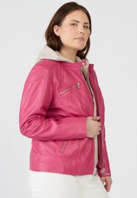 Rosa läderjacka med en figurnära design, utrustad med huva och fickor med dragkedja. Märkbart sömnadsdetaljer och en slät yta.
