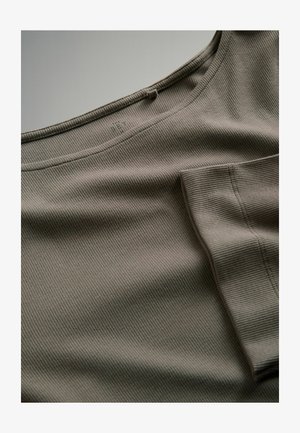 Prążkowany zielono-brązowy materiał z okrągłym dekoltem i kieszenią po boku. Charakteryzuje się subtelnym wzorem tekstury na całej powierzchni materiału.