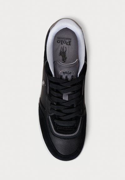 Adidași negri care prezintă o combinație de piele netedă și suede, vârf rotunjit, talpă albă contrastantă și șireturi negre. Logo-ul este vizibil pe limba șiretului.