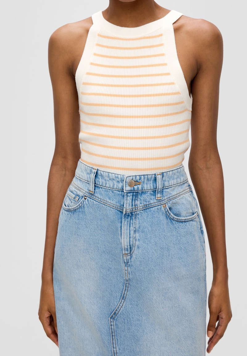 Top de tirantes blanco con ribetes, con rayas horizontales naranjas, que presenta un cuello alto y un diseño sin mangas, combinado con una falda de mezclilla azul clara.