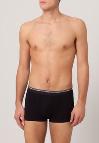 Sorte boxer briefs lavet af bomuld, med en grå elastisk talje med "JOCKEY" gentaget. Glat tekstur, tætsiddende design.