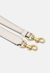 Leather bag strap in cream with contrast stitching. Features gold-tone metal clips at each end for attachment. Smooth texture, minimal design.