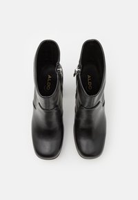 Black leather ankle boots with a smooth finish, square toe, and side zipper detailing. Features subtle stitching and a padded interior.