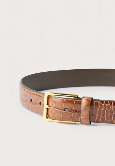 Ceinture en cuir marron avec texture crocodile et boucle rectangulaire dorée posée à plat sur un fond blanc.