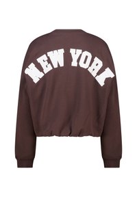 Brown cropped sweatshirt featuring "NEW YORK" text in large white letters across the back. Ribbed cuffs and waistband. Soft fabric texture.