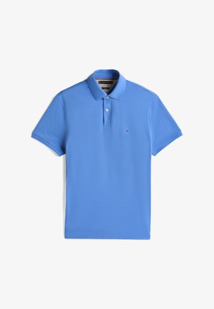 Lyseblå poloshirt med krage, korte ermer og teksturert stoff. Har en liten logo på venstre bryst.