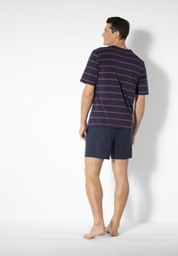 Navy striped t-shirt with red lines, short sleeves, and a round neck paired with navy shorts, shown from the back. Barefoot on a white background.