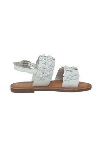 Sandali bianchi in pelle con un design a fiore a più strati, punta aperta e cinturino alla caviglia. Suola marrone, design flat, stile casual.