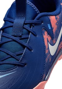 Scarpa sportiva blu con tomaia sintetica testurizzata, accenti a macchie rosa, logo swoosh grigio e un intricato design dei lacci.