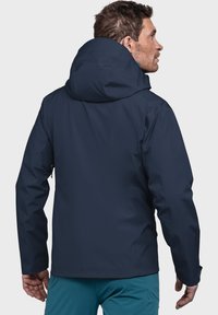 Marineblaue wasserdichte Jacke mit Kapuze, ausgestattet mit einer glatten Textur, verstellbaren Manschetten und einem eleganten Design, von hinten gezeigt.