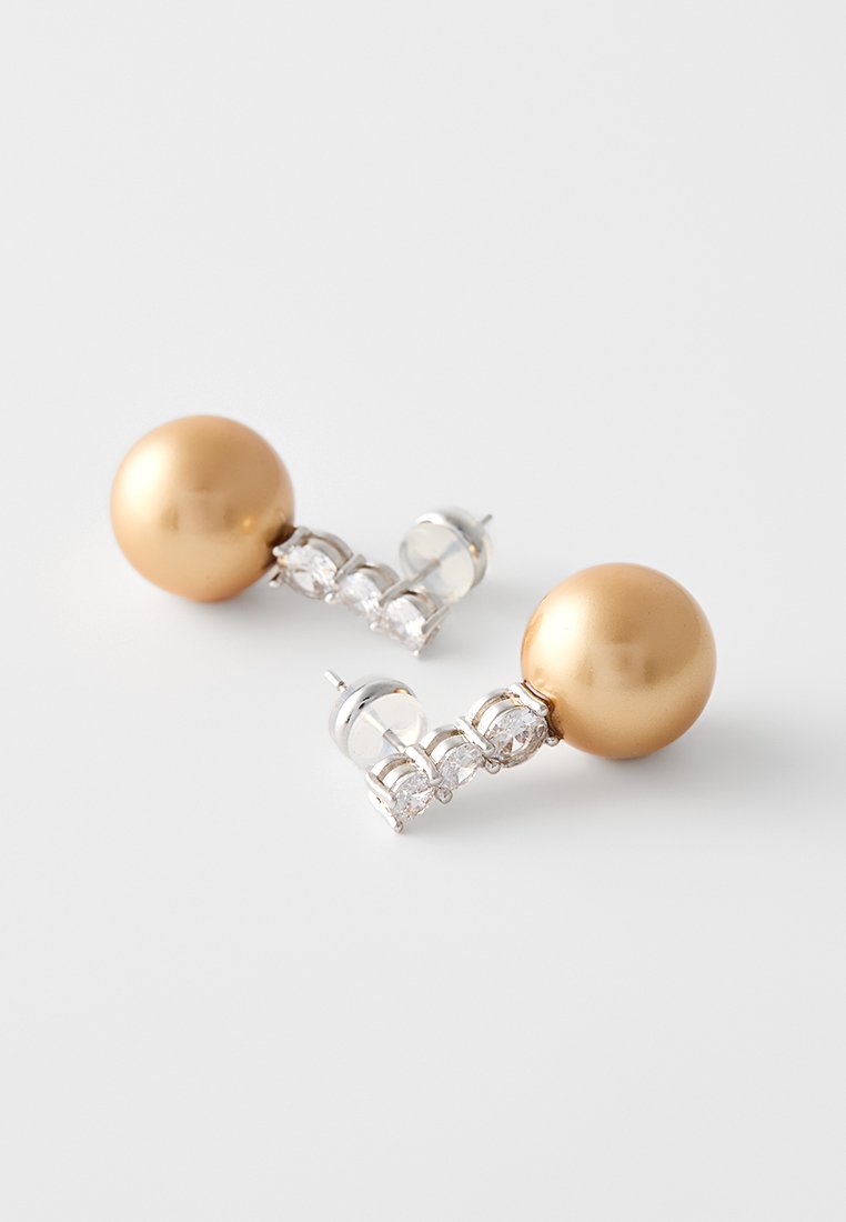 Pendientes esféricos de oro con una fila de tres acentos de piedra transparente. Los stud de plata unen el diseño, ofreciendo un acabado pulido.