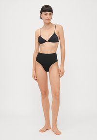 Zwart bikini set met een driehoekige bralette-top met dunne bandjes en een hoge taille onderkant, gemaakt van een gladde stof met een matte afwerking.