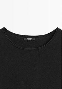 Chemise noire Massimo Dutti avec encolure ronde et étiquette de marque visible au col, fabriquée en Chine, présentée sur un fond blanc.