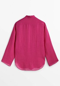 Chemise rose vif à manches longues avec un ourlet arrondi et un petit col, vue de dos sur fond blanc.
