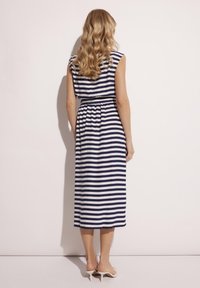 Granatowa i biała, w paski, długa sukienka z dopasowaną talią, rękawami w formie krótkich rąk oraz luźnym krojem. Miękka tkanina o gładkiej strukturze.