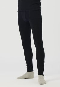 Leggings negros hechos de una tela elástica, con un diseño ajustado y textura suave. Combinados con calcetines grises hasta el tobillo sobre un fondo claro.