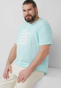 Lichtblauw T-shirt met korte mouwen met witte grafische tekst en surfplankontwerp. Gemaakt van zachte stof, heeft een relaxte pasvorm en een ronde hals.