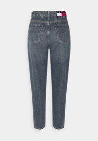 Jeans de mezclilla de lavado oscuro con una cintura alta, piernas ajustadas, dos bolsillos traseros y una cinturilla que presenta una etiqueta de marca en rojo, blanco y azul.
