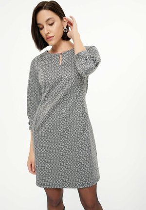 Grau gemustertes Kleid mit Dreiviertelärmeln, einem Schlüsselloch-Ausschnitt und einem leicht ausgestellt geschnittenen Saum. Hergestellt aus einem strukturierten Stoff mit Rautenmuster.