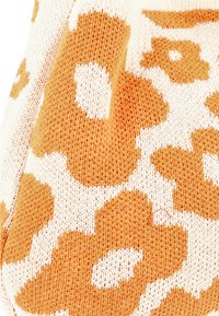 Strikket stof med et orange og cremefarvet blomstermønster. Teksturen er blød med en let løs vævning, der fremhæver designet.