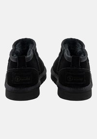 Botas de tobillo de ante negro con un suave forro de felpa, detalles cosidos y acentos de tela. Suela de goma plana con etiqueta de la marca en la parte trasera.