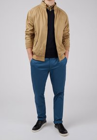 Brun bomberjakke, marineblå sweater, ternet skjorte, blå bukser, sorte sneakers; glat stof, lynlåslukning, ribbede manchetter.