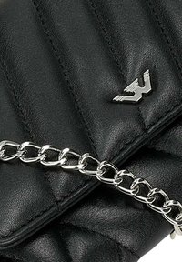 Sac en cuir noir matelassé avec une bandoulière en chaîne argentée et un accent logo métallique. La texture est lisse avec des coutures en relief.