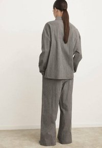 Set coordinato a quadri grigi composto da giacca dal taglio morbido con colletto e pantaloni a gamba larga, realizzato in tessuto texturizzato.
