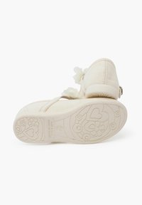Zapatos de tela blancos con acentos florales, parte superior texturizada y suela de goma con patrones de corazones y flores. Incluye una correa ajustable.