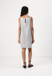 Rochie fără mâneci, cu dungi gri, cu un decolteu la spate, design până la genunchi și material texturat, asociată cu pantofi negri cu șireturi.