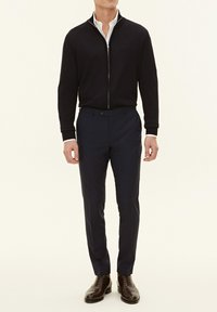 Dark navy zip-up sweater over a white collared shirt, paired with tailored navy pants and brown dress shoes. Smooth fabric with fitted design.
