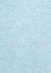 Jasnoniebieska dzianina o miękkiej teksturze, z delikatnym melanżowym wzorem i jednolitą gęstością ściegów w całej powierzchni.