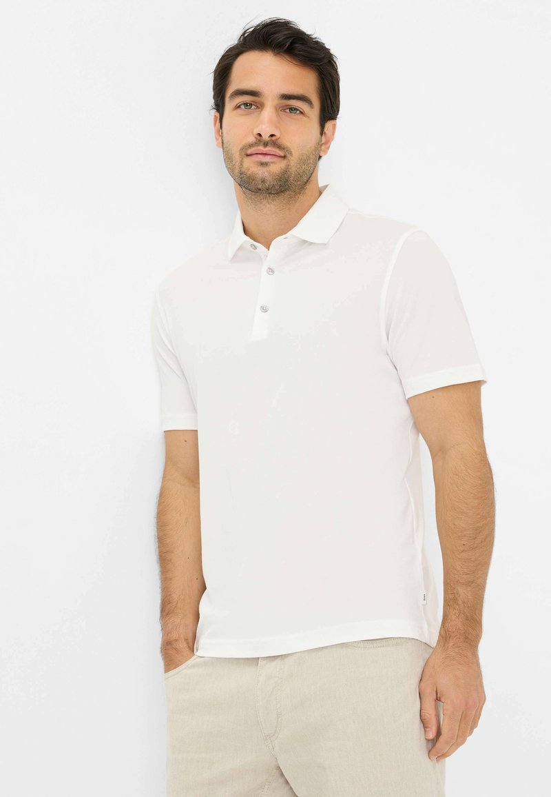 Hvid kortærmet polo-shirt med klassisk krave, tre-knaps lukning og glat stof. Sammen med lyse bukser.