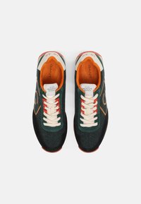 Sneakers verde scuro con motivo a spina di pesce, lacci crema, dettagli arancioni e neri. Presentano un interno imbottito per il comfort.