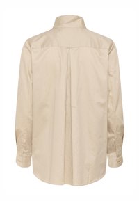 Chemise beige à manches longues avec poignets boutonnés, dotée d'un empiècement dos et d'un pli central, présentée sur fond blanc.